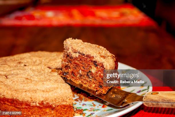 cinnamon cake stuffed with assorted nuts with a spatula removing a slice cake. - walnut cake stock pictures, royalty-free photos & images