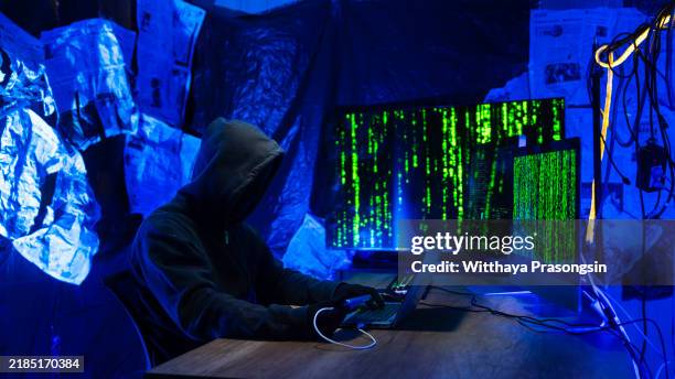 hacker in dark room with digital code on monitors - data breach stock pictures, royalty-free photos & images