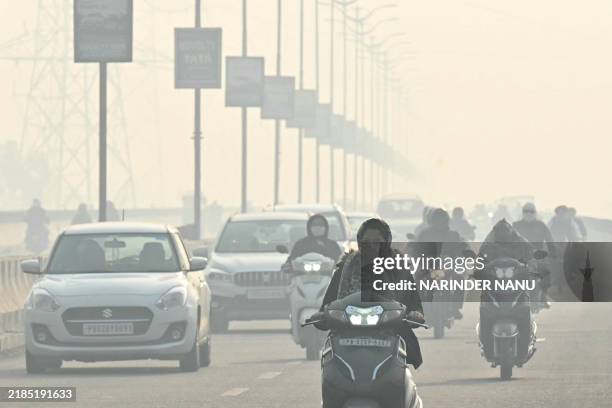 Commuters make their way amid thick smog along a street in Amritsar on November 21, 2024.