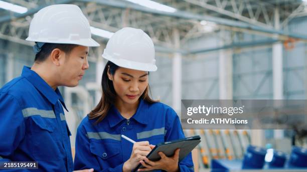 équipe d’ingénieurs collaborant avec des tablettes dans un entrepôt industriel - geste de la main photos et images de collection