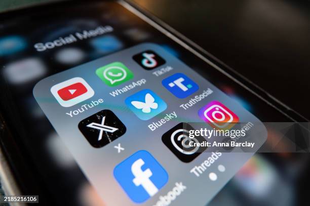 In this photo illustration a smartphone screen displays the logo of social media app Bluesky besides the logo of US online social media and social...