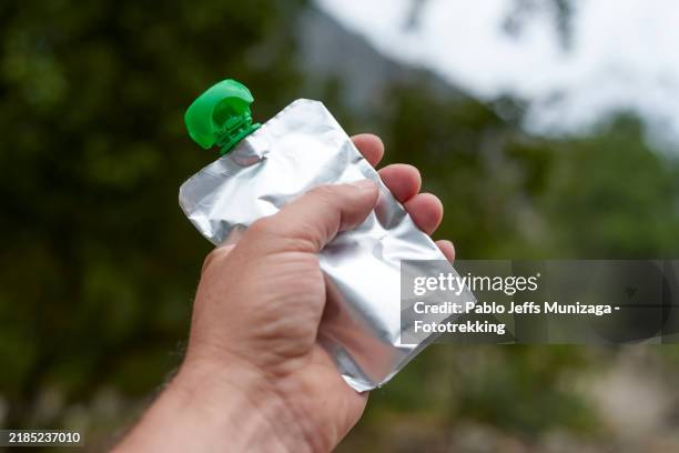hiker holding foil pouch with green cap for energy snack - gel pack stock pictures, royalty-free photos & images