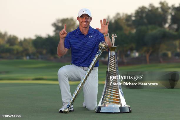 Rory McIlroy of Northern Ireland poses with the DP World Tour Championship trophy and the Race to Dubai trophy on the 18th green whilst gesturing...
