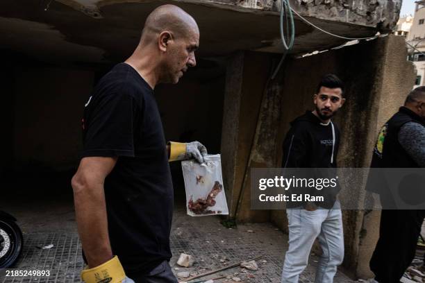 Man carries a bag thought to contain human remains of a victim of the strike as civil defence workers, locals and Lebanese Armer Forces soldiers...