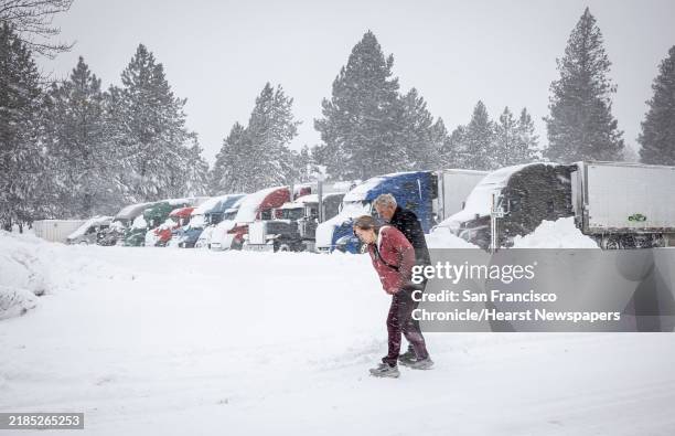 Truckers Duane Tevelde and Tiffene Hanson brave the wind and snow on their way along Shastina Drive in Weed, Calif., where dozens of truckers have...