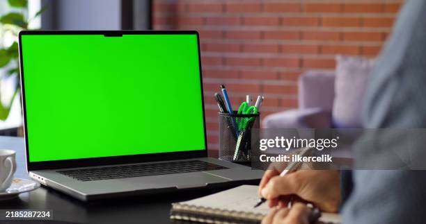 man using laptop computer with a chroma key green screen in the office and taking notes - green screen stock pictures, royalty-free photos & images