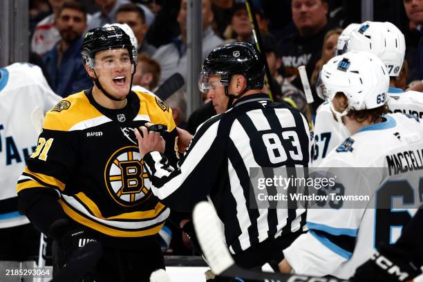 Nikita Zadorov of the Boston Bruins is held back by linesman Matt MacPherson as he exchanges words with Lawson Crouse of the Utah Hockey Club during...