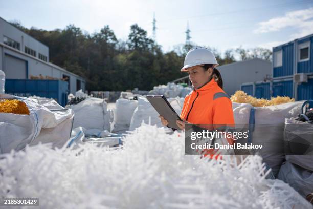 worker inspecting polymer resin pellets in recycling factory - afvalverwerking stockfoto's en -beelden