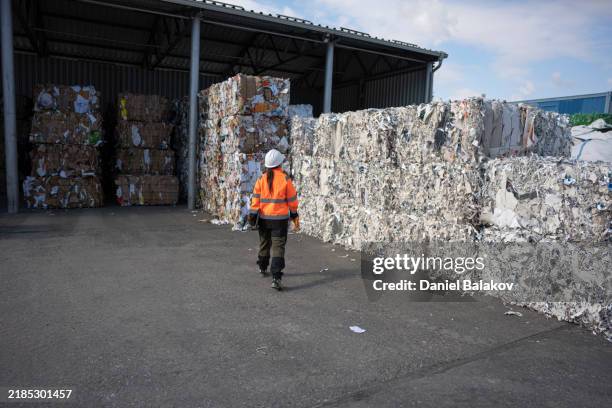 worker inspects bales of sorted recycled materials in factory - circulaire economie stockfoto's en -beelden