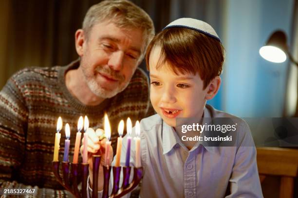 55 year old man celebrates hanukkah with his son - hanukkah stock pictures, royalty-free photos & images