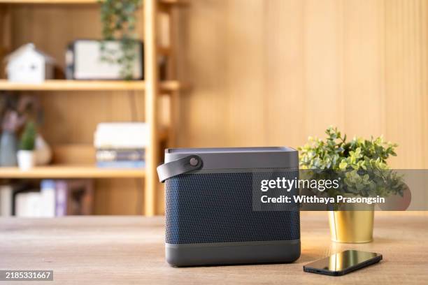 modern bluetooth speaker on wooden table with smartphone and plant - lumière ambiante photos et images de collection