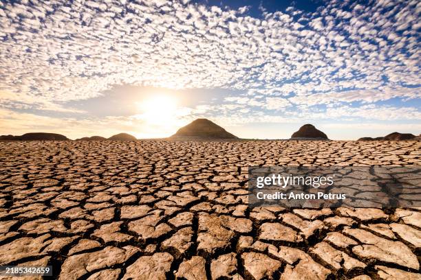 sunset over cracked soil in the desert. global warming concept - umweltkatastrophe stock-fotos und bilder