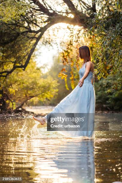 mid-adult woman playing in a shallow river in a forest - long dress stock pictures, royalty-free photos & images