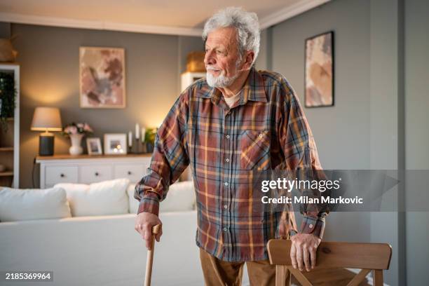 wisdom of the year - senior man with a walking stick, leaning on a chair - walking cane stock pictures, royalty-free photos & images