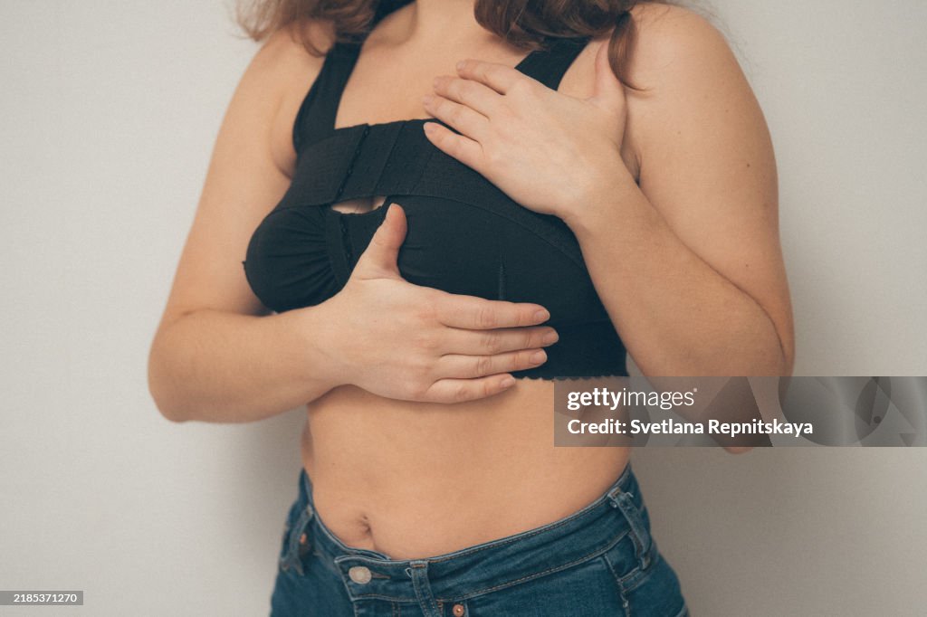 Woman applying on a bandage after mammoplasty