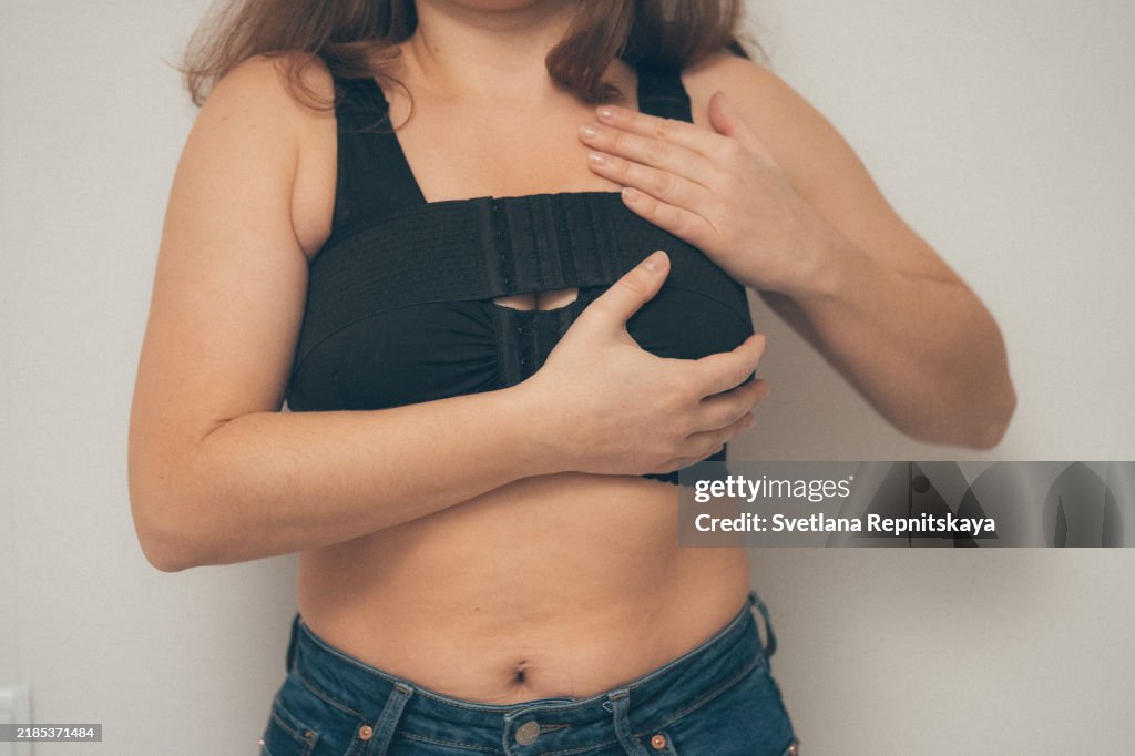 Woman applying on a bandage after mammoplasty