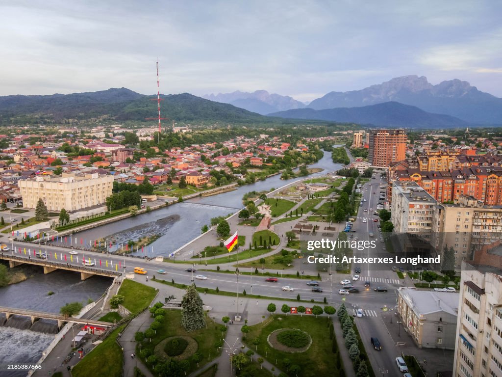 The view of Vladikavkaz, the capital city of North Ossetia - Alania, Russia, with Terek river, regional flag and Caucasus mountains