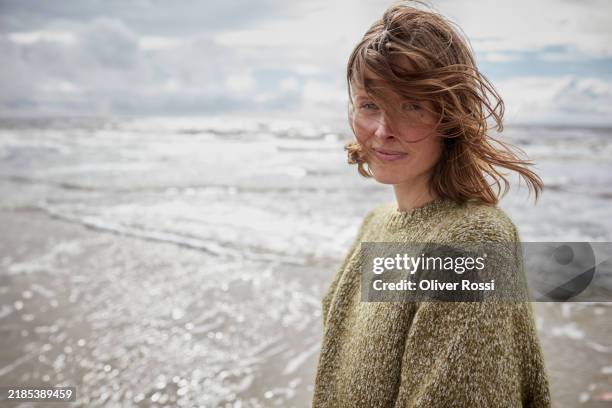 portrait of woman with tousles hair by the sea - natürlicher zustand stock-fotos und bilder