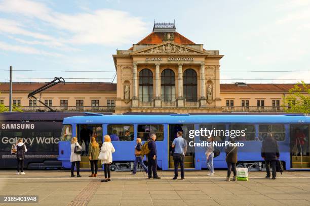 Vibrant scene unfolds at Zagreb Central Station in Zagreb, Croatia, on April 27 where a blue tram halts at the bustling tram stop. Passengers wait to...