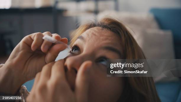 caucasian woman applying eye drops indoors - conjunctivitis stock pictures, royalty-free photos & images