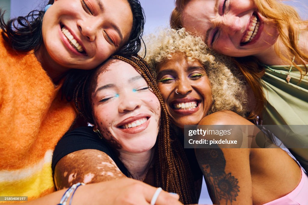 Four diverse Gen Z women embracing and smiling with eyes closed. Beauty and wellness concept.