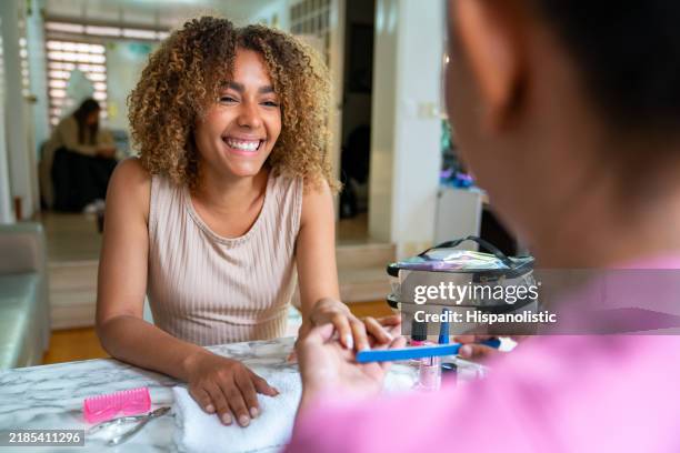 beautiful woman getting a manicure at a nail salon and smiling - african american nails stock pictures, royalty-free photos & images