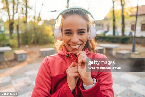 une belle femme de 29 ans, belle et joyeuse, qui fait de l’exercice dans le parc par une froide journée d’automne. - joggeuse photos et images de collection