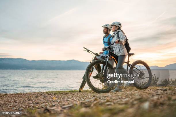 seaside adventure at sunrise with diverse couple and e-bikes - elcykel bildbanksfoton och bilder
