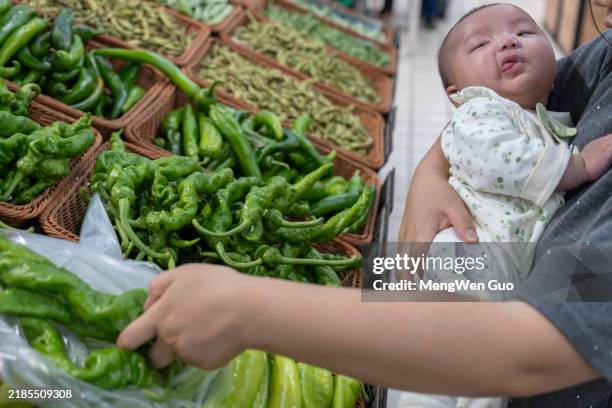 mother holding baby to buy groceries - asian market stock pictures, royalty-free photos & images