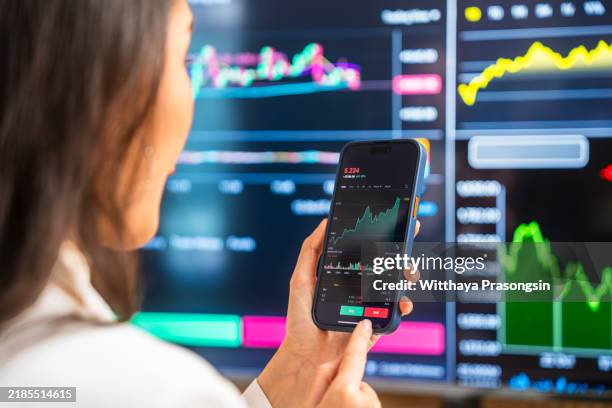 businesswoman analyzing financial data on mobile device in office - corretor de bolsa imagens e fotografias de stock
