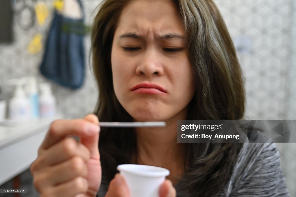 Cropped shot view of unhappy woman while using a LH ovulation test strip. Tests Strips give accurate and clear results for the possibility of pregnancy.