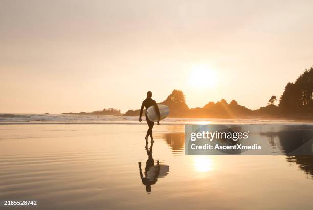 un surfeur lointain se promène sur une longue plage - pacific rim national park reserve photos et images de collection