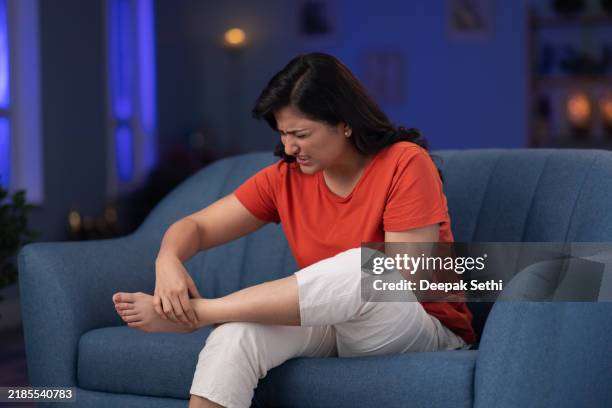woman ankle pain sitting on sofa at home stock photo - bone stock pictures, royalty-free photos & images