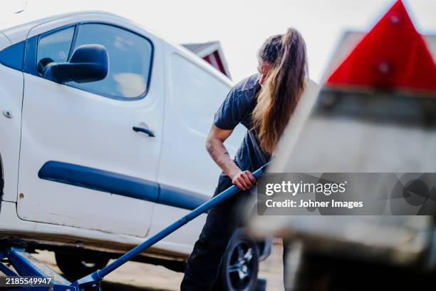 female mechanic lifting vehicle using car jack - car jack stock pictures, royalty-free photos & images