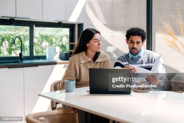 young couple cooperating while going through their home finances. - plan financiero fotografías e imágenes de stock