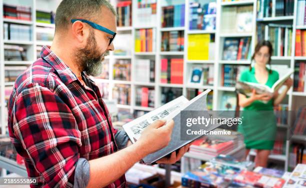 homme lisant une bande dessinée dans un magasin de bandes dessinées - salon du livre photos et images de collection