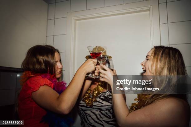female friends toasting wineglasses while enjoying party at home - rubbing alcohol stock pictures, royalty-free photos & images