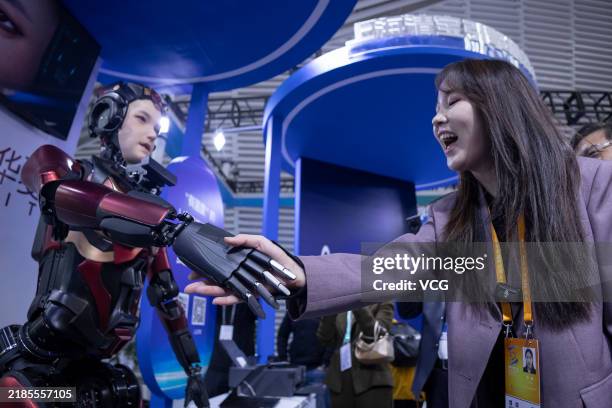 Visitor shakes hands with a humanoid robot at the Light of Internet Expo on November 19, 2024 in Wuzhen, Jiaxing City, Zhejiang Province of China....
