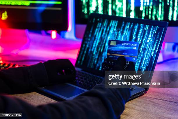 hacker stealing credit card information from laptop in dark room - wirtschaftskriminalität stock-fotos und bilder