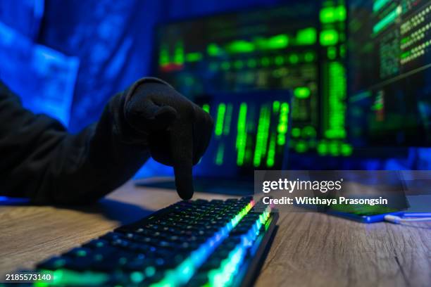 hacker in dark room typing on illuminated keyboard - data breach stock pictures, royalty-free photos & images
