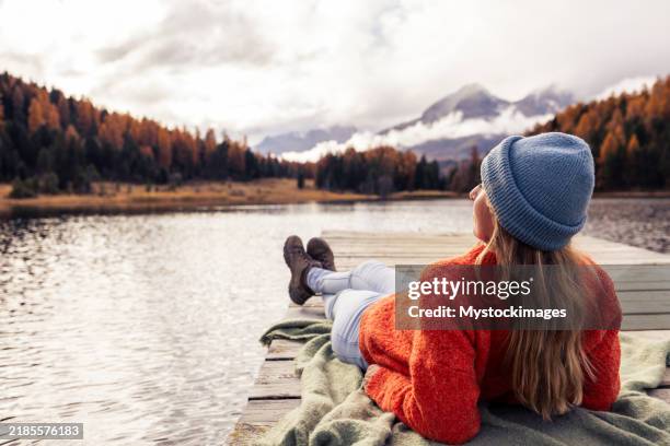 woman relaxing on a dock overlooking a mountain lake - emotional wellbeing stock pictures, royalty-free photos & images