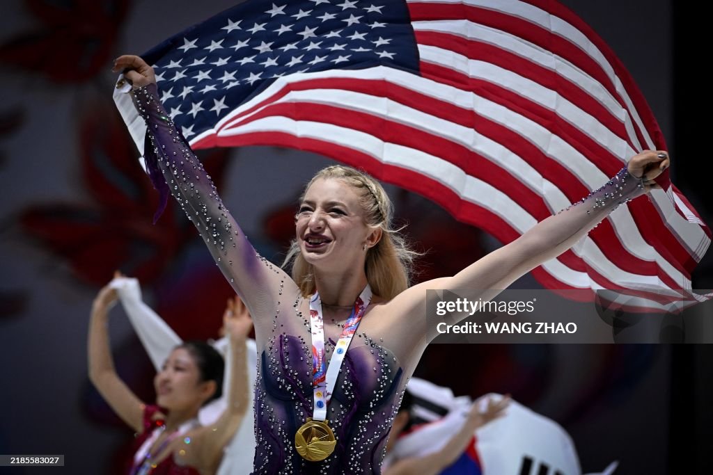 Gold medallist US' Amber Glenn poses with her national flag during