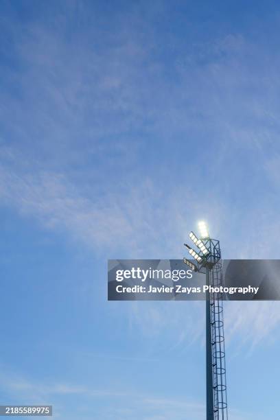 stadium lights at sunset against blue sky, bright lights. - im scheinwerferlicht gefangen stock-fotos und bilder