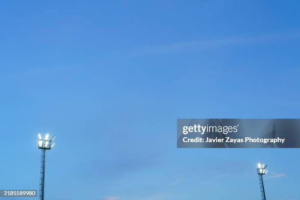 stadium lights at sunset against blue sky, bright lights. - im scheinwerferlicht gefangen stock-fotos und bilder