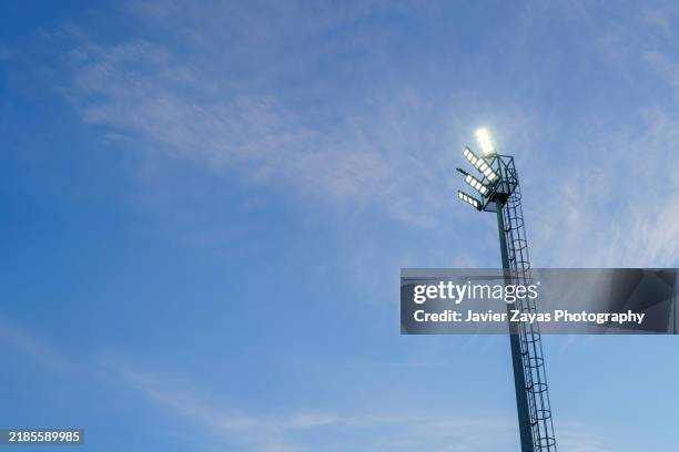 stadium lights at sunset against blue sky, bright lights. - reflector objeto fabricado fotografías e imágenes de stock