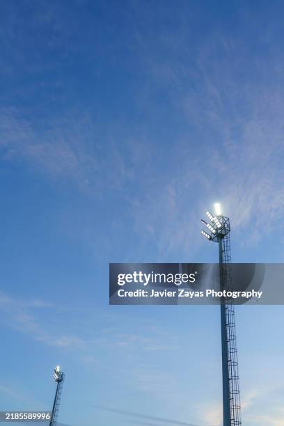 stadium lights at sunset against blue sky, bright lights. - im scheinwerferlicht gefangen stock-fotos und bilder