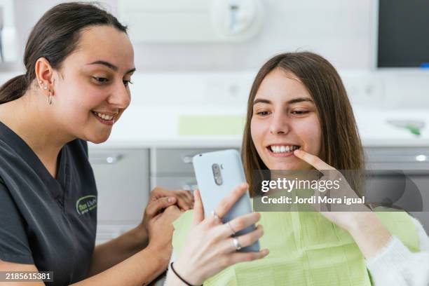 dentist showing teeth treatment results to patient on smartphone in dental clinic - before and after teeth stock pictures, royalty-free photos & images