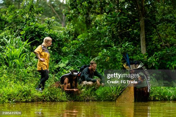 indigenous woman showing how to use trap to catch fish during a tourist expedition outdoors - amazone stockfoto's en -beelden