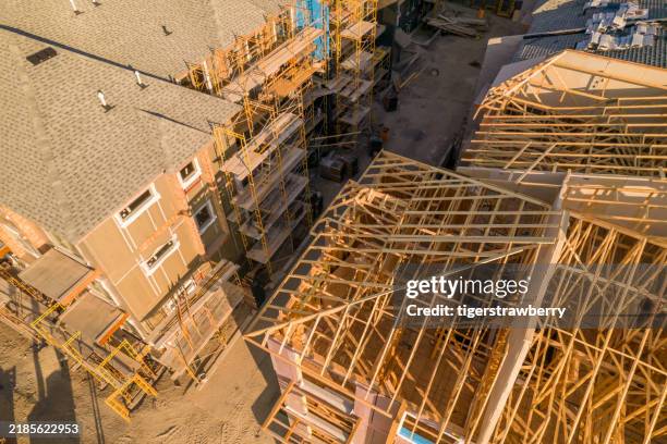 Modern North American home in construction. Aerial view of unfinished city house with wooden roof ribs frame structure. Roof beams under construction.