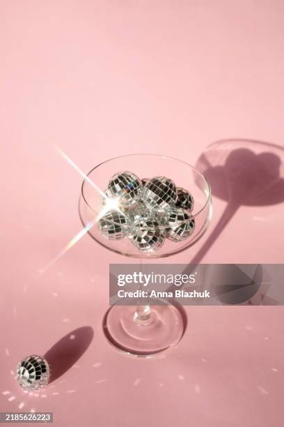 champagne flute or glass with mirror disco balls in bright direct light on pink background. new year party. - globo espelhado imagens e fotografias de stock